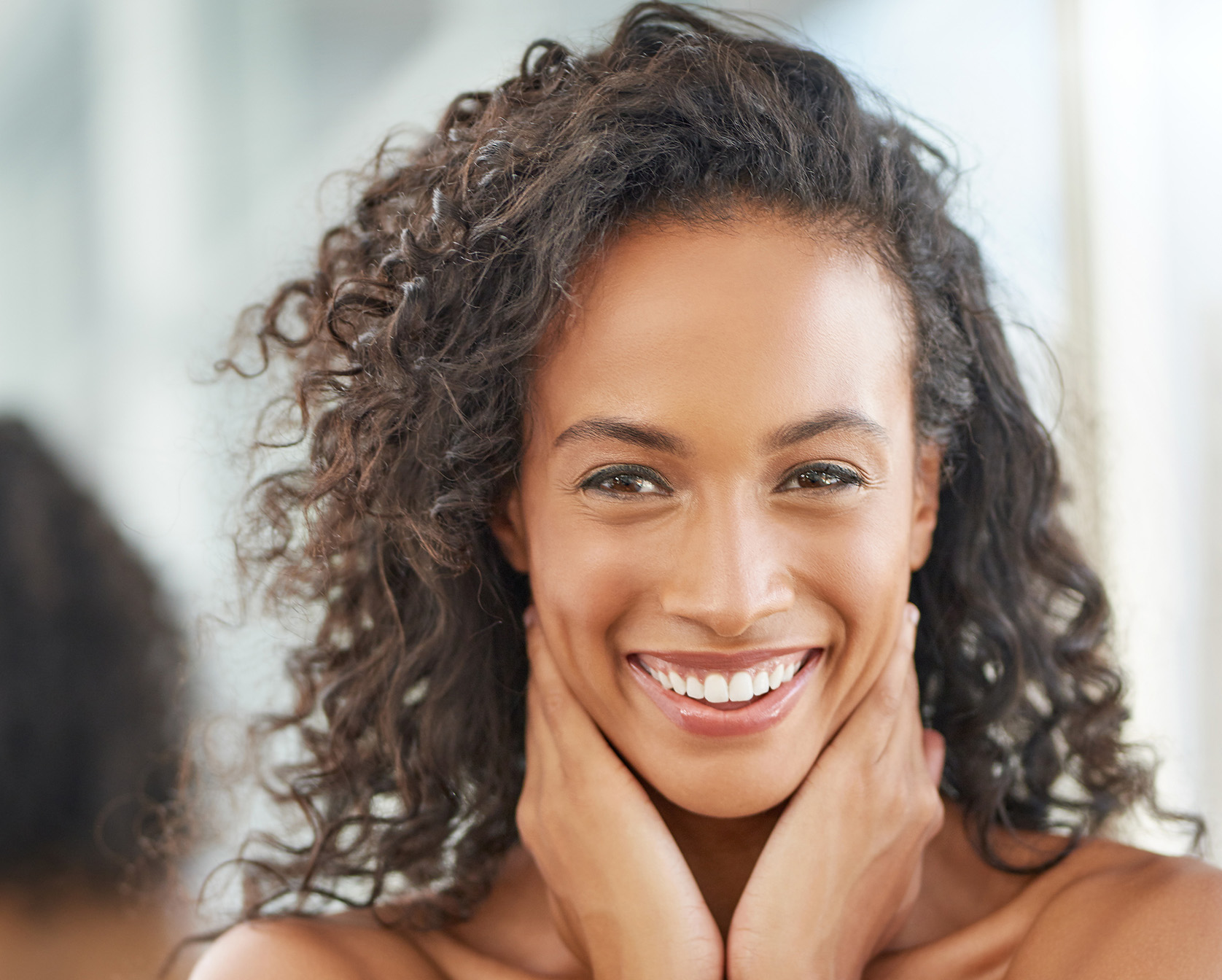 smiling woman with curly hair and a white shirt looking at the camera